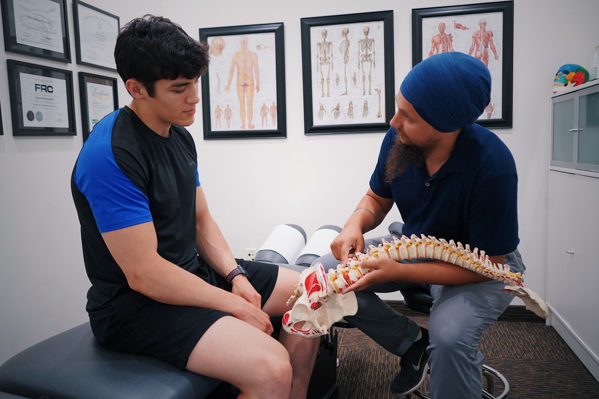 A doctor explains spinal issues to a patient using a spine model