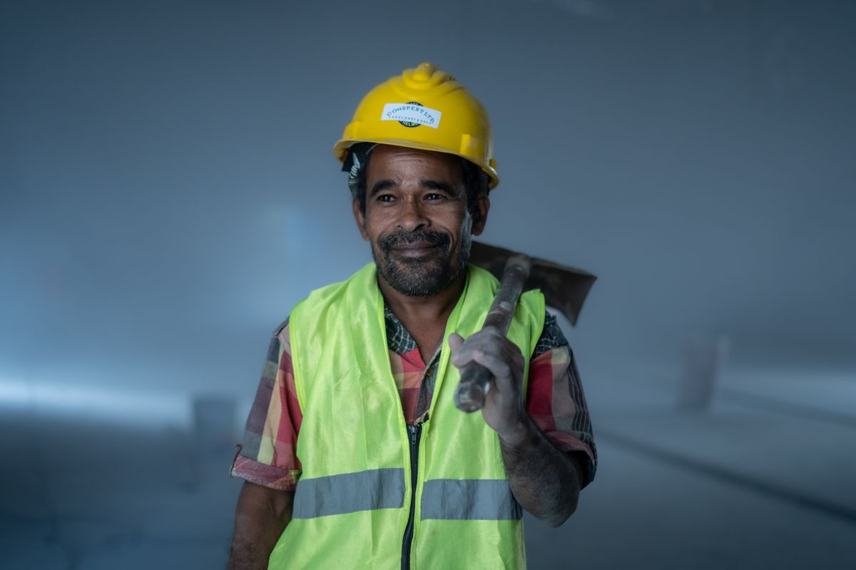 Smiling construction worker in safety gear holding a tool indoors
