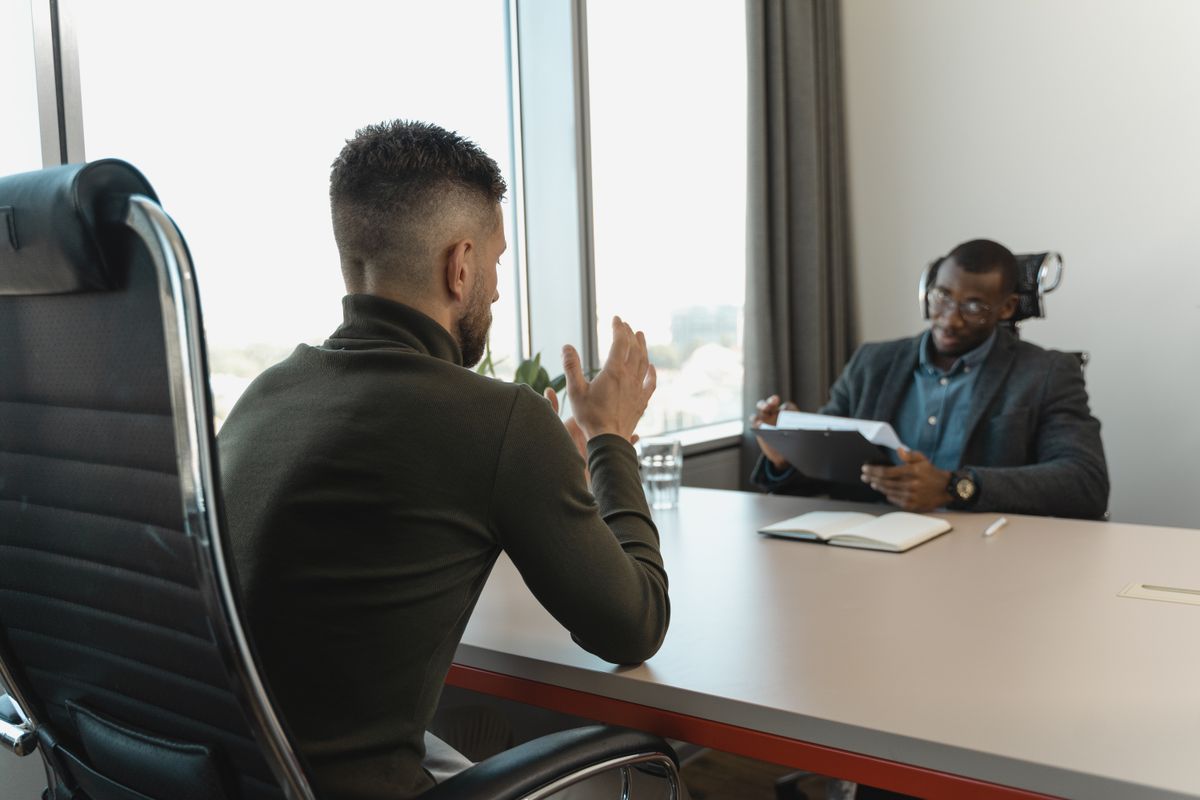 Two men in a job interview setting in a modern office with large windows