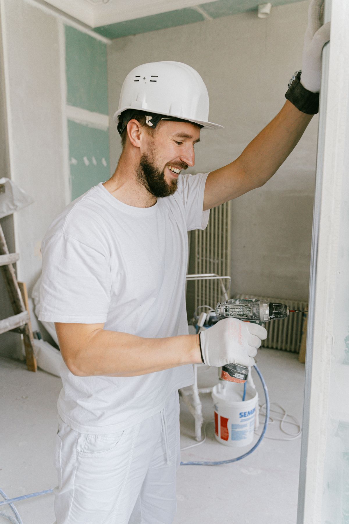 Happy construction worker using a drill indoors during renovation