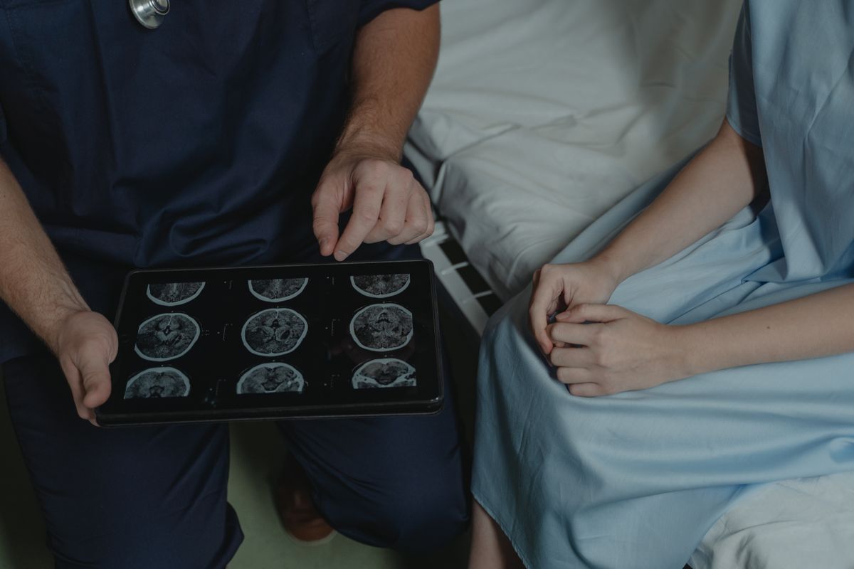 A doctor shows and explains brain scan images to a patient in a medical setting