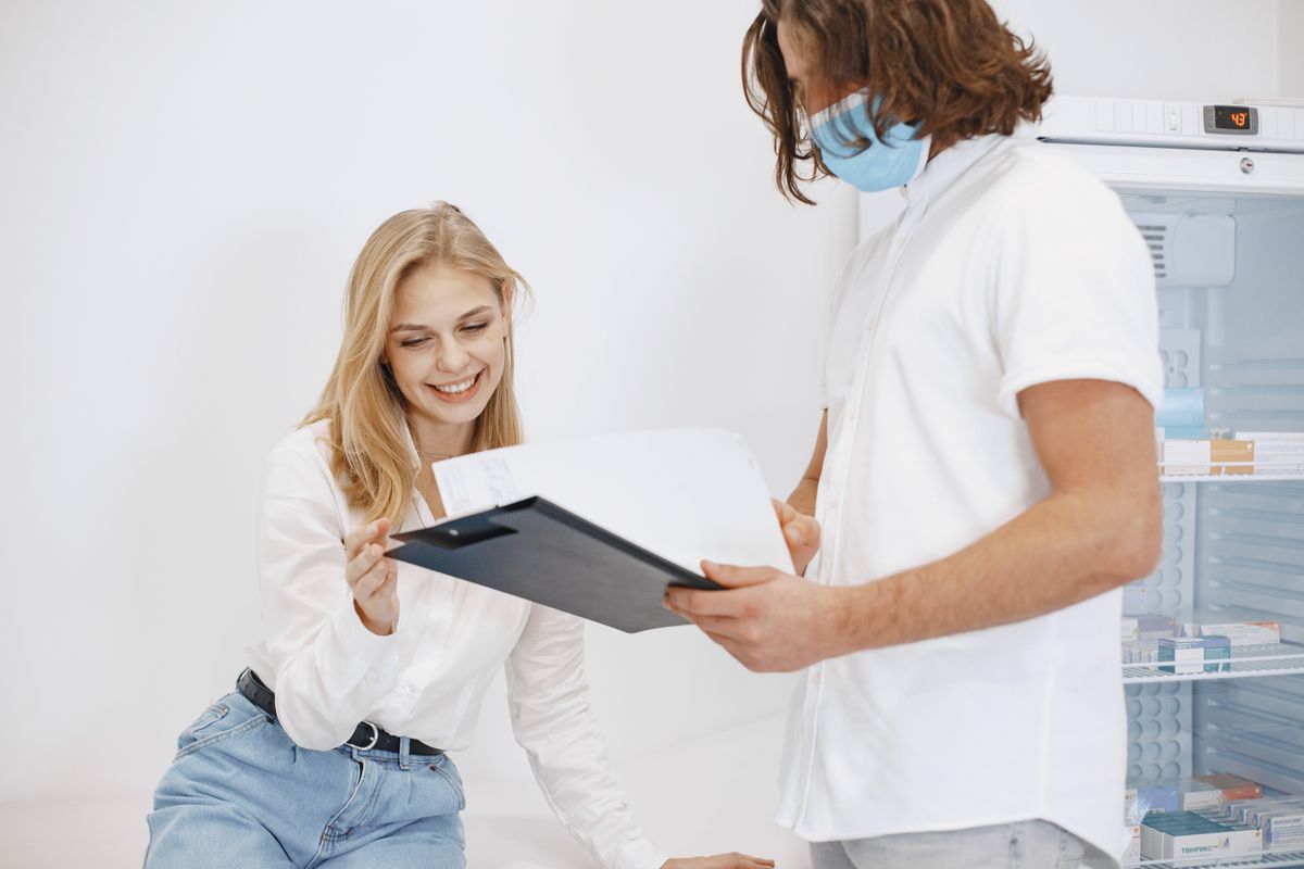A patient happily reviews her medical results with a doctor in a clinic setting