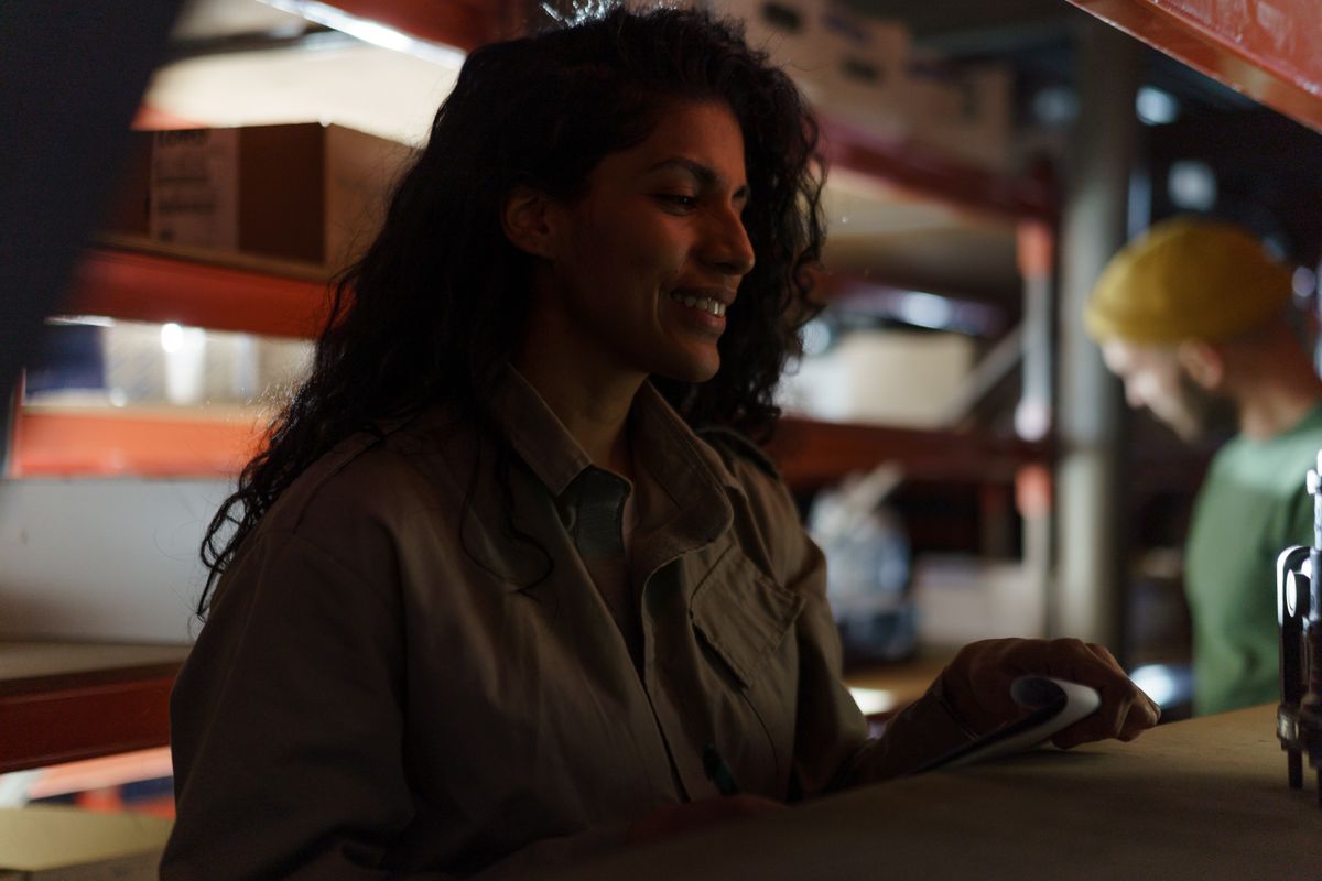 Smiling female worker examines inventory in a dimly lit warehouse
