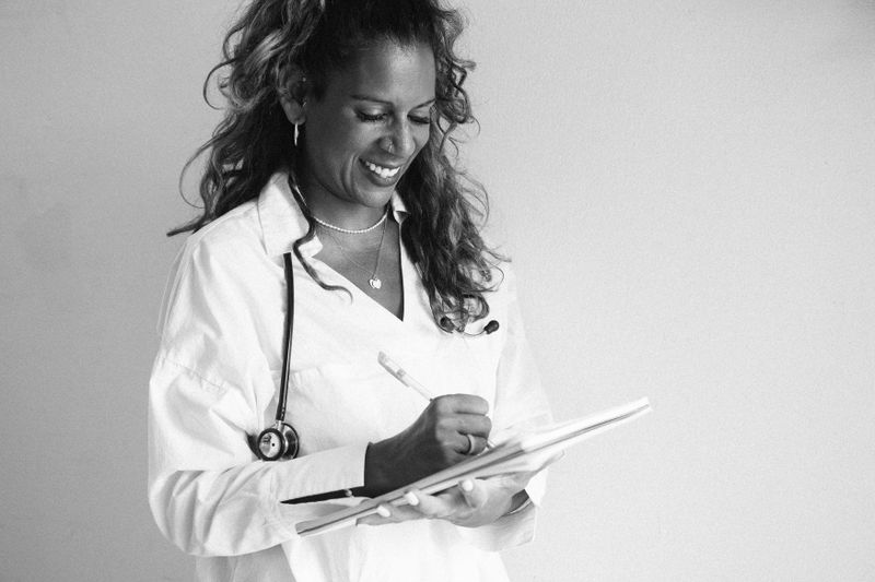 Cheerful female doctor writing in her notebook in black and white portrait