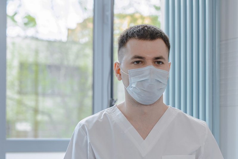 Medical professional in scrubs consulting with a patient while taking notes