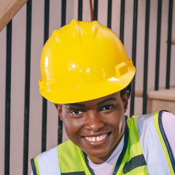 Smiling construction worker holding ear plugs and wearing PPE