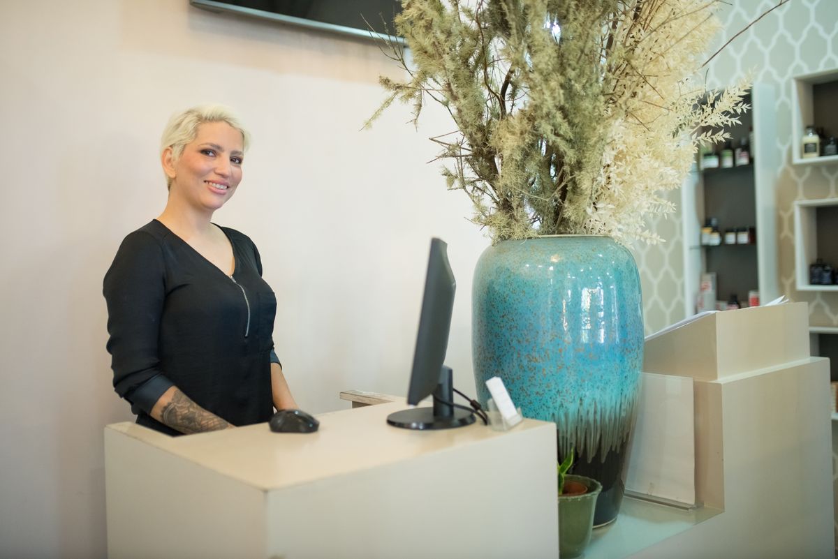 Friendly female receptionist at a stylish hair salon front desk in Portugal