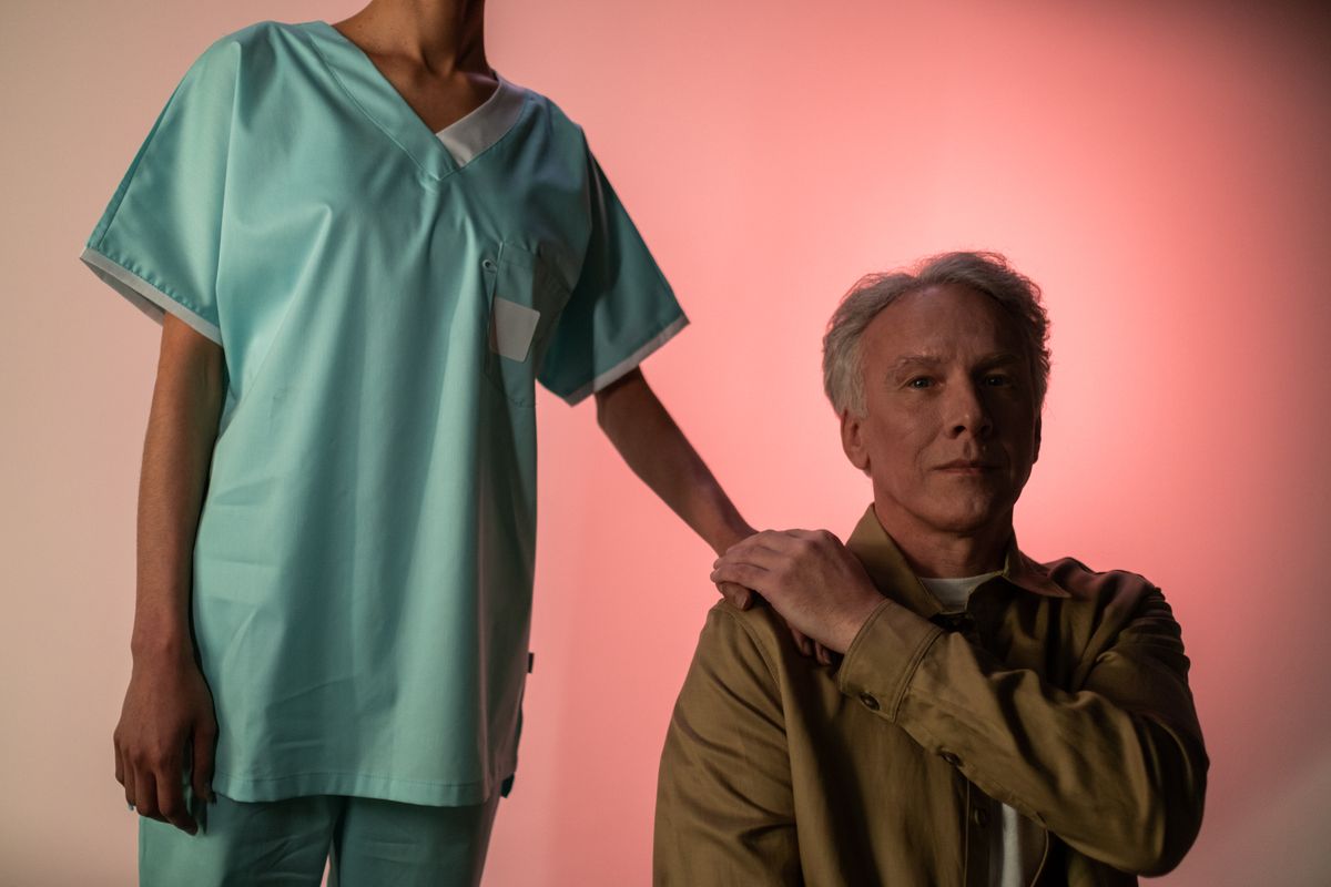 Portrait of an elderly man with a caregiver in medical attire